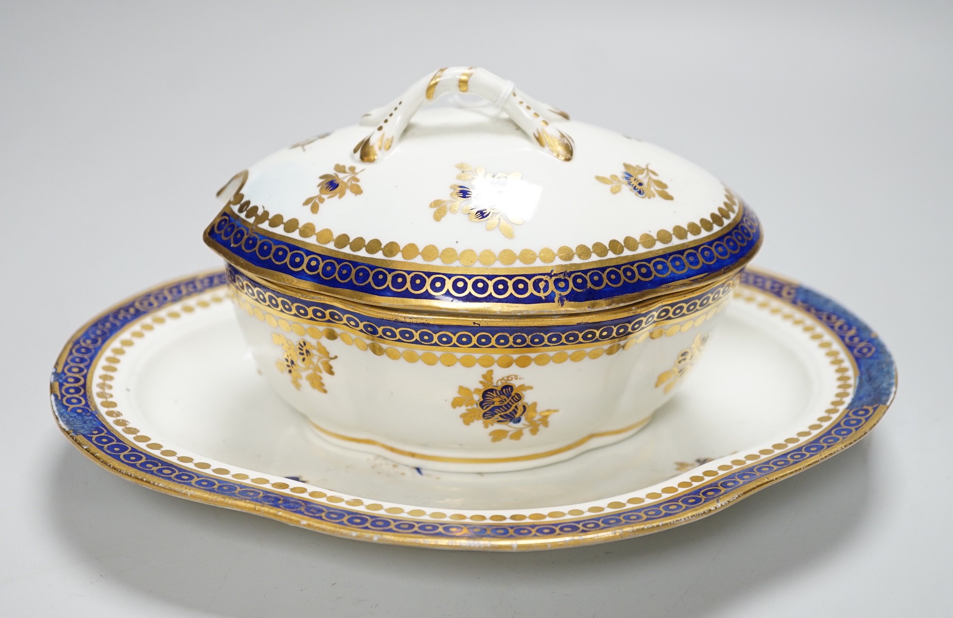 An 18th century Caughley tureen cover and stand with blue and gilt decoration, stand mis-fired to border, S mark to stand and base, stand 23cms wide